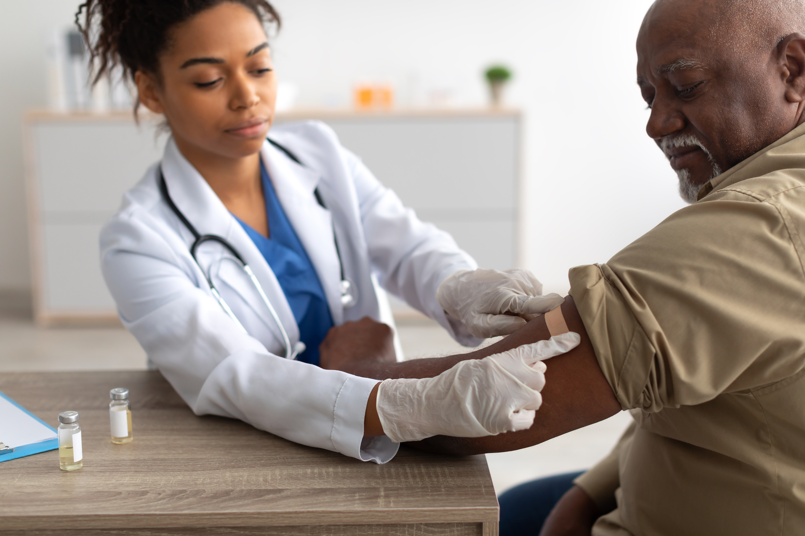 Black Mature Man Getting Vaccinated, Doctor Applying Adhesive Bandage